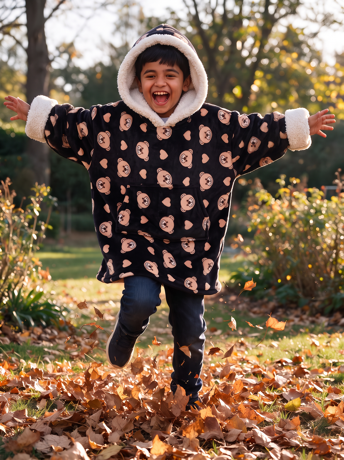 Hugsy Kids Teddy Bear Black wearable blanket hoodie, playing in the garden